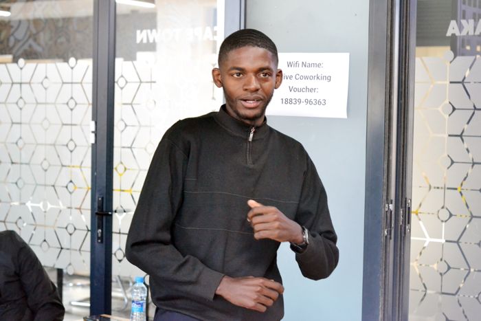 A participant in a black quarter-zip sweater shares a point with the room.
