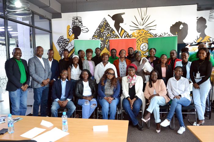 Facilitators, guests and SME owners gather for a group photo in front of the venue’s African-print mural and three roll-up banners.