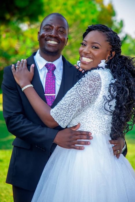 A close-up of the couple laughing together, her hand on his chest, his purple patterned tie and her sparkling bodice in focus.