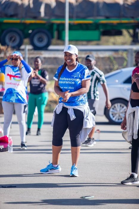 A smiling participant in a blue “Professional Insurance” shirt and white cap enjoys an outdoor exercise session.